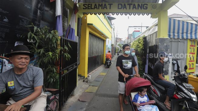 Warga berjalan di kawasan Kampung Sentra Kreatif, RW 006 Kota Bambu Selatan, Palmerah, Jakarta, Rabu (3/11/2021). [Suara.com/Angga Budhiyanto]