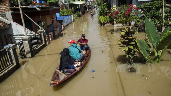 Warga menaiki perahu untuk melintasi genangan banjir di Dayeuhkolot, Kabupaten Bandung, Jawa Barat, Minggu (3/11/2021). ANTARA FOTO/Novrian Arbi