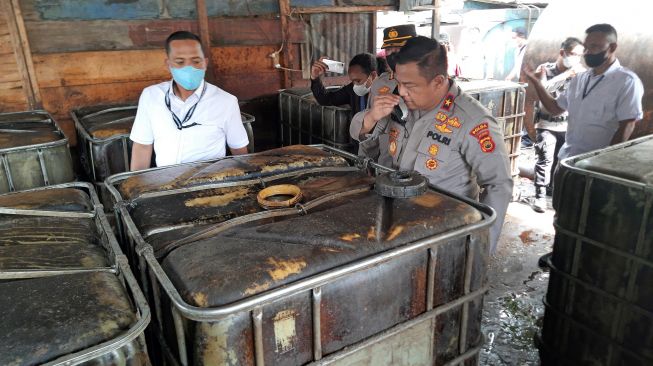 Wakapolda Jambi Brigjen Pol Yudawan (tengah) memeriksa aroma minyak yang disimpan dalam beberapa wadah saat razia tempat pengoplosan minyak mentah ilegal di Mendalo Darat, Jambi Luar Kota, Muarojambi, Jambi, Rabu (3/11/2021).  ANTARA FOTO/Wahdi Septiawan