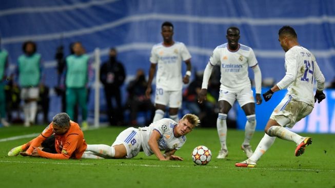 Gelandang Real Madrid asal Jerman, Toni Kroos (tengah) terjatuh saat Casemiro (kanan) bersiap untuk menembak bola dalam matchday keempat Grup D Liga Champions antara Real Madrid vs Shakhtar Donetsk di stadion Santiago Bernabeu, 4 November 2021.OSCAR DEL POZO / AFP.