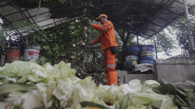 Petugas penanganan prasarana dan sarana umum (PPSU) mencampur sampah organik untuk diolah menjadi pupuk kompos di Tempat Pengolahan Sampah Terpadu Grogol Selatan, Kebayoran Lama, Jakarta, Kamis (4/11/2021). [Suara.com/Angga Budhiyanto]