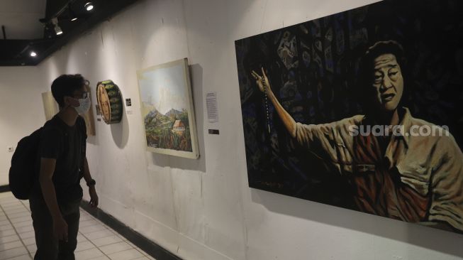 Pengunjung mengamati lukisan yang ditampilkan dalam pameran bertajuk "Hai, Kamu!", di Balai Budaya, Jakarta, Kamis (4/11/2021). [Suara.com/Angga Budhiyanto]