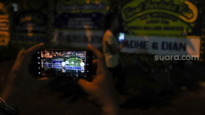 Warga memfoto Karangan bunga di rumah duka Vanessa Angel di Kembangan, Jakarta Barat, Kamis (4/11/2021). [Suara.com/Alfian Winanto]