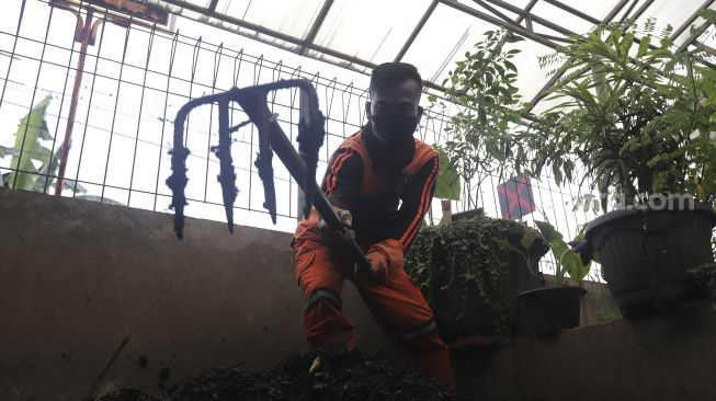 Petugas penanganan prasarana dan sarana umum (PPSU) mengaduk pupuk kompos di Tempat Pengolahan Sampah Terpadu Grogol Selatan, Kebayoran Lama, Jakarta, Kamis (4/11/2021). [Suara.com/Angga Budhiyanto]