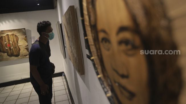 Pengunjung mengamati lukisan yang ditampilkan dalam pameran bertajuk "Hai, Kamu!", di Balai Budaya, Jakarta, Kamis (4/11/2021). [Suara.com/Angga Budhiyanto]