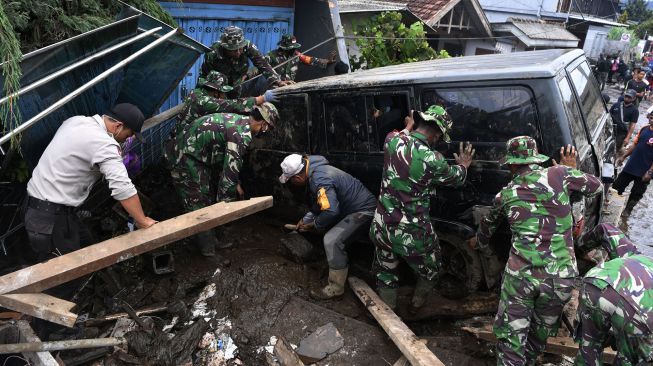 Anggota Polisi dan TNI berusaha mengamankan sebuah mobil yang terperosok akibat banjir bandang di Bulukerto, Kota Batu, Jawa Timur, Jumat (5/11/2021). ANTARA FOTO/Zabur Karuru
