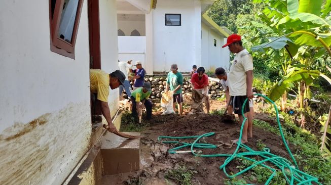 Warga Kutayasa kerja bakti membersihkan lumpur yang masuk rumah pasca banjir bandang akibat sungai meluap di Banjarnegara, Jumat (5/11/2021). [Suara.com/Citra Ningsih]