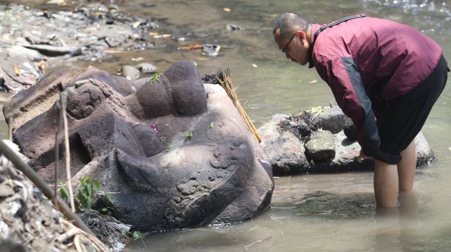 Warga mengamati kepala arca Kala yang ditemukan di aliran sungai Desa Nambaan, Kediri, Jawa Timur, Sabtu (6/11/2021).  ANTARA FOTO/Prasetia Fauzani
