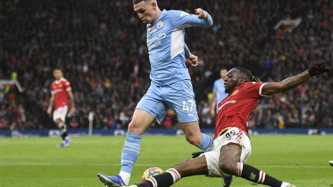 Bek Manchester United Aaron Wan-Bissaka (kanan) menantang gelandang Manchester City Phil Foden selama pertandingan sepak bola Liga Premier Inggris antara Manchester United dan Manchester City di Old Trafford, Manchester, Inggris, Sabtu (6/11/2021). [OLI SCARFF / AFP]