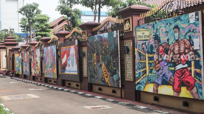 Kendaraan melintas di depan mural yang berisi kritik terhadap Polri di Jalan Trunojoyo, Jakarta Selatan, Sabtu (6/11/2021). [Suara.com/Alfian Winanto]