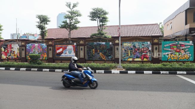 Kendaraan melintas di depan mural yang berisi kritik terhadap Polri di Jalan Trunojoyo, Jakarta Selatan, Sabtu (6/11/2021). [Suara.com/Alfian Winanto]