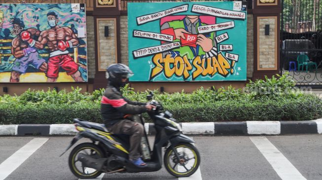 Kendaraan melintas di depan mural yang berisi kritik terhadap Polri di Jalan Trunojoyo, Jakarta Selatan, Sabtu (6/11/2021). [Suara.com/Alfian Winanto]