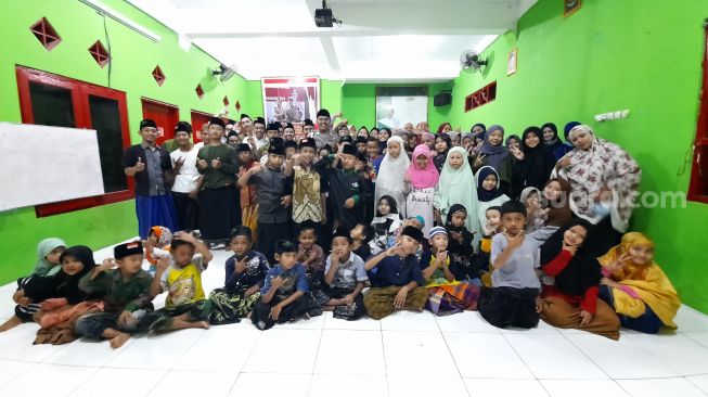 Bripka Nur Ali Suwandhi berfoto bersama anak asuhnya di Rumah Singgah Bumi Damai, Jalan Purbayan, Kemantren Kotagede, Kota Jogja, Minggu (7/11/2021). - (SuaraJogja.id/Muhammad Ilham Baktora)