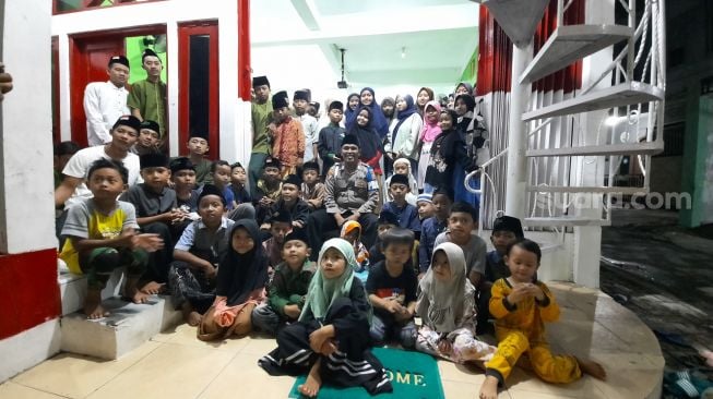 Bripka Nur Ali Suwandhi berfoto bersama anak asuhnya di Rumah Singgah Bumi Damai, Jalan Purbayan, Kemantren Kotagede, Kota Jogja, Minggu (7/11/2021). - (SuaraJogja.id/Muhammad Ilham Baktora)