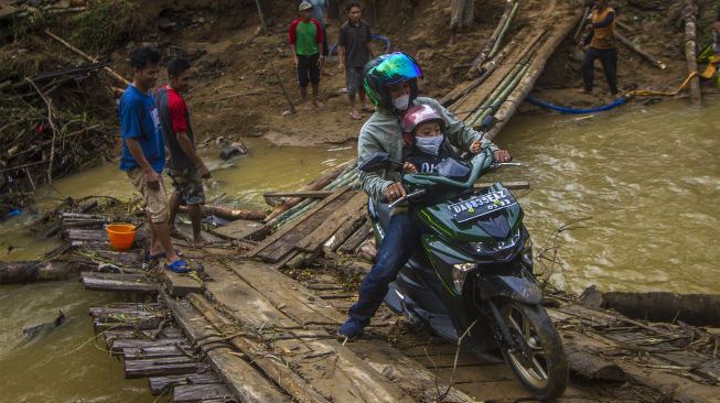 Pengendara motor melintasi jembatan darurat di Desa Murung B, Kecamatan Hantakan, Kalimantan Selatan, Senin (8/11/2021). [ANTARA FOTO/Bayu Pratama S]