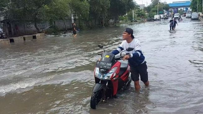 Seorang pemotor memaksa menerjang genangan air akibat banjir rob di ruas jalan menuju Pelabuhan Muara Baru, Penjaringan, Jakarta Utara, Senin (8/11/2021). [ANTARA/Abdu Faisal]