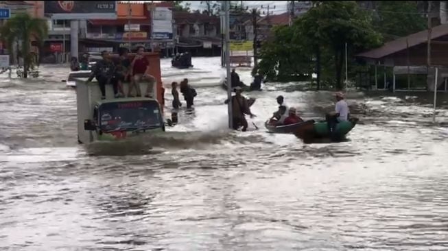 Truk nekat menerjang banjir di Jalan Lintas Melawi, Sintang membawa warga terdampak banjir pada Senin (8/11/2021). [Istimewa]