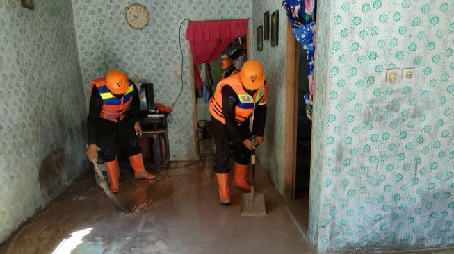 Personel Brimob Polda Sumut membersihkan rumah warga terdampak banjir di Sergai. [dok: humas Brimob Polda Sumut]