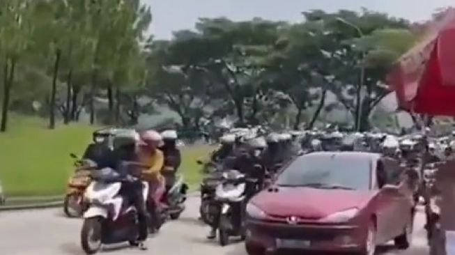 Pemotor terlihat marah dan mengepung sedan merah di Sentul.[Twitter]