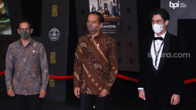 Presiden Republik Indonesia, Ir. H. Joko Widodo (tengah) ditemani Menteri Pendidikan dan Kebudayaan, Nadiem Makarim (Kiri) dan Aktor Reza Rahadian (kanan) saat tiba di gelaran Festival Film Indonesia di JCC Senayan, Jakarta Pusat, Rabu (10/11/2021). [Suara.com/Alfian Winanto]