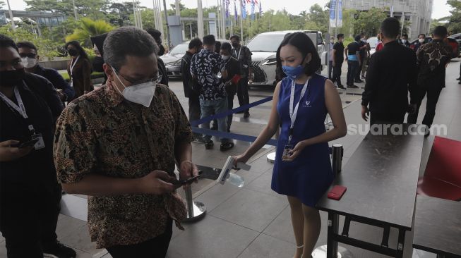 Petugas menyemprotkan cairan disinfektan kepada pengunjung yang akan memasuki area pameran otomotif GAIKINDO Indonesia International Auto Show (GIIAS) 2021 di Indonesia Convention Exhibition (ICE) BSD, Serpong, Tangerang, Banten, Kamis (11/11/2021). [Suara.com/Angga Budhiyanto]