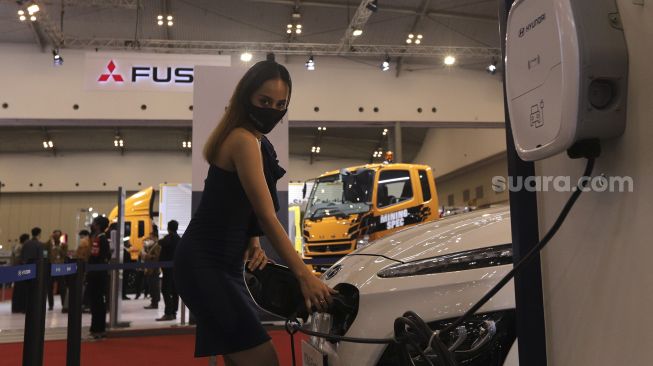 Model berpose di depan kendaraan yang dipamerkan dalam pameran otomotif GAIKINDO Indonesia International Auto Show (GIIAS) 2021 di Indonesia Convention Exhibition (ICE) BSD, Serpong, Tangerang, Banten, Kamis (11/11/2021). [Suara.com/Angga Budhiyanto]