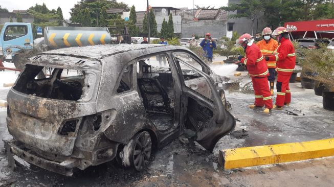 Petugas berusaha memadamkan api pada mobil mewah di Rest Area Tol Japek, Jumat (12/11/2021). [Ist]