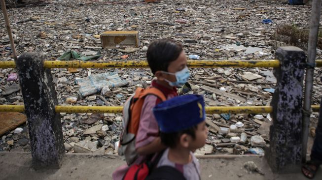 Warga berjalan di samping sampah yang menumpuk di Kali Dadap yang dipenuhi sampah di Kosambi, Kabupaten Tangerang, Banten, Jumat (12/11/2021). ANTARA FOTO/Fauzan