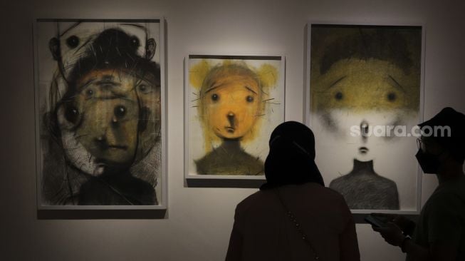 Pengunjung melihat karya seni yang ditampilkan dalam pameran seni bertajuk Daydreaming Face di RUCI Art Space, Kebayoran Baru, Jakarta, Sabtu (13/11/2021). [Suara.com/Angga Budhiyanto]