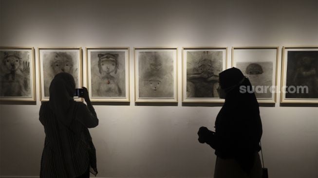 Pengunjung melihat karya seni yang ditampilkan dalam pameran seni bertajuk Daydreaming Face di RUCI Art Space, Kebayoran Baru, Jakarta, Sabtu (13/11/2021). [Suara.com/Angga Budhiyanto]