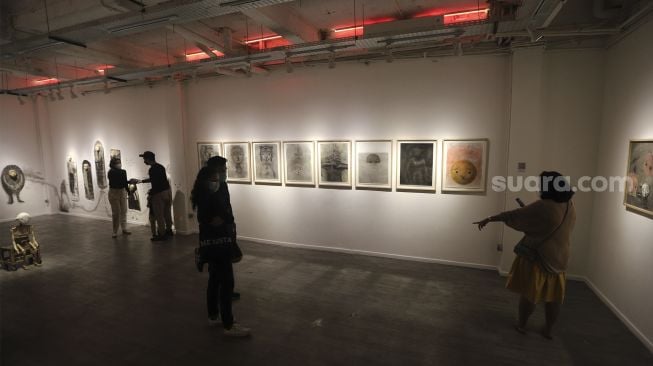 Pengunjung melihat karya seni yang ditampilkan dalam pameran seni bertajuk Daydreaming Face di RUCI Art Space, Kebayoran Baru, Jakarta, Sabtu (13/11/2021). [Suara.com/Angga Budhiyanto]