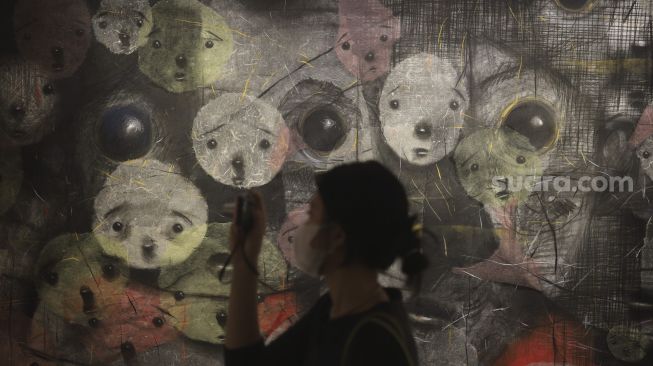 Pengunjung memotret karya seni yang ditampilkan dalam pameran seni bertajuk Daydreaming Face di RUCI Art Space, Kebayoran Baru, Jakarta, Sabtu (13/11/2021). [Suara.com/Angga Budhiyanto]