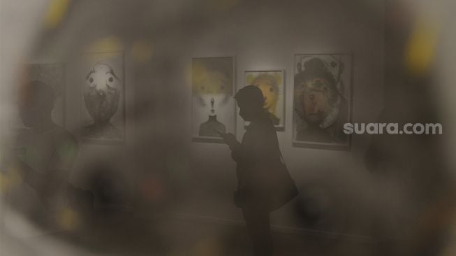 Refleksi pengunjung melihat karya seni yang ditampilkan dalam pameran seni bertajuk Daydreaming Face di RUCI Art Space, Kebayoran Baru, Jakarta, Sabtu (13/11/2021). [Suara.com/Angga Budhiyanto]