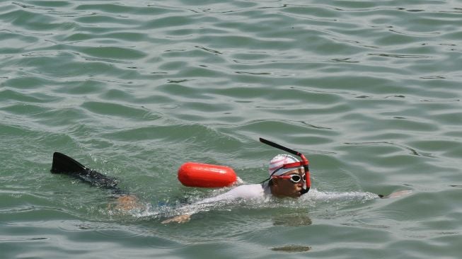 Peserta renang beradu cepat menuju garis finish saat mengikuti lomba renang lintas Teluk Palu di Palu, Sulawesi Tengah, Minggu (14/11/2021).  ANTARA FOTO/Mohamad Hamzah