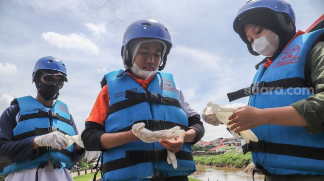 Anggota Forum Alumni Sispala DKI Jakarta (FASTA) berkolaborasi dengan Sekolah Sungai Jakarta (SSJ) dan Siswa Pencinta Alam (Sispala) bersiap untuk membersihkan sungai di Bantaran Kali Ciliwung, Jakarta Selatan, Minggu (14/11/2021). [Suara.com/Alfian Winanto]