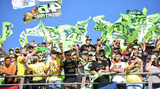 Fans pebalap Italia Valentino Rossi bersorak dari tribun selama balapan MotoGP Grand Prix Valencia di arena pacuan kuda Ricardo Tormo di Cheste, pada 14 November 2021. 
JOSE JORDAN / AFP