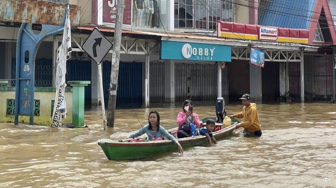 Warga berusaha menerobos jalan yang terendam banjir di Tanjung Puri, Kabupaten Sintang, Kalimantan Barat, Minggu (14/11/2021). ANTARA FOTO/Jane Elisabeth Wuysang