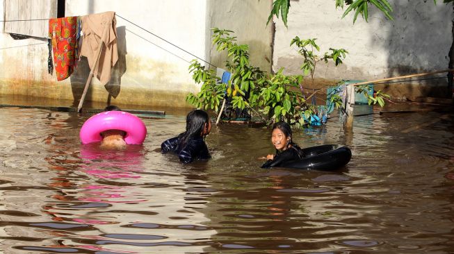 Sejumlah anak berenang di lapangan volley yang terendam banjir di Desa Semuntai, Kabupaten Sanggau, Kalimantan Barat, Senin (15/11/2021).  ANTARA FOTO/Jessica Helena Wuysang