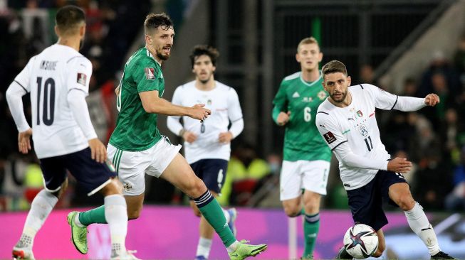 Striker Italy Lorenzo Insigne (kiri) dan striker Italia Domenico Berardi (kanan) bersaing dengan bek Irlandia Utara Craig Cathcart selama pertandingan sepak bola kualifikasi Grup C putaran satu Piala Dunia FIFA 2022 antara Irlandia Utara dan Italia di Windsor Park di Belfast, Irlandia Utara pada November 15, 2021.Paul Faith / AFP