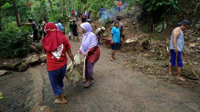 Warga membersihkan material tanah longsor yang menutup jalan Gunung Kelir-Kutogiri di Perbukitan Menoreh, Girimulyo, Kulon Progo, D.I Yogyakarta, Selasa (16/11/2021). ANTARA FOTO/Andreas Fitri Atmoko
