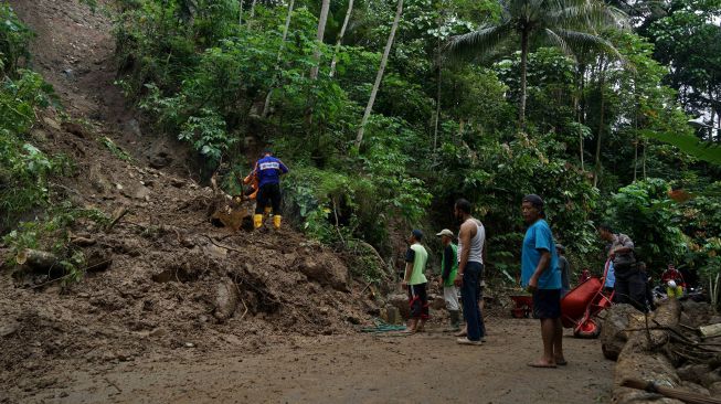 Polisi dan warga membersihkan material tanah longsor yang menutup jalan Gunung Kelir-Kutogiri di Perbukitan Menoreh, Girimulyo, Kulon Progo, D.I Yogyakarta, Selasa (16/11/2021). ANTARA FOTO/Andreas Fitri Atmoko