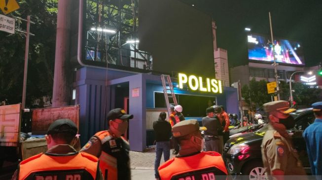 Satpol PP DKI Jakarta membongkar papan reklame LED di atas bangunan Pos Polisi Simpang Harmoni, Jakarta Pusat, Senin (6/9/2021) malam. [ANTARA]