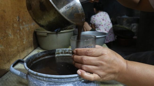 Seorang karyawan Jamu Ginggang tengah menyedu salah satu produk jamunya. [suarajogja.id]