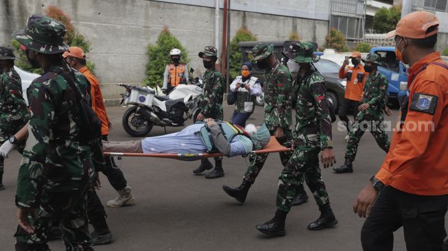 Petugas gabungan mengevakuasi korban saat simulasi penanganan banjir di halaman Universitas Borobudur, Kalimalang, Cipinang Melayu, Jakarta, Rabu (17/11/2021). [Suara.com/Angga Budhiyanto]