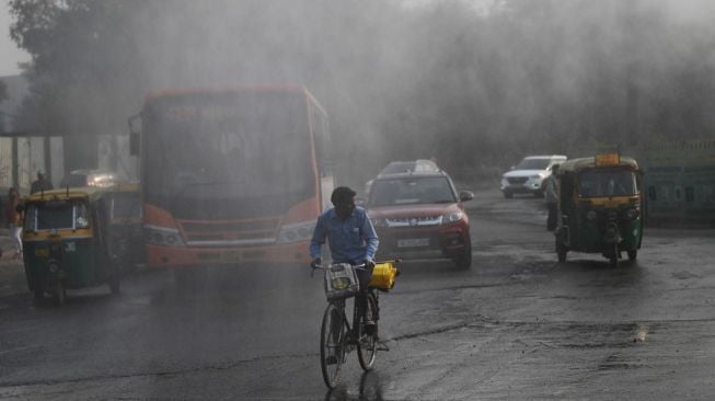 Warga Delhi melewati jalanan di tengah pekatnya asap akibat polusi udara. Ibu Kota India itu meliburkan sekolah serta kampus pada Selasa (16/11/2021) setelah indeks kualitas udara melonjak ke level beracun. [AFP/Money Sharma]