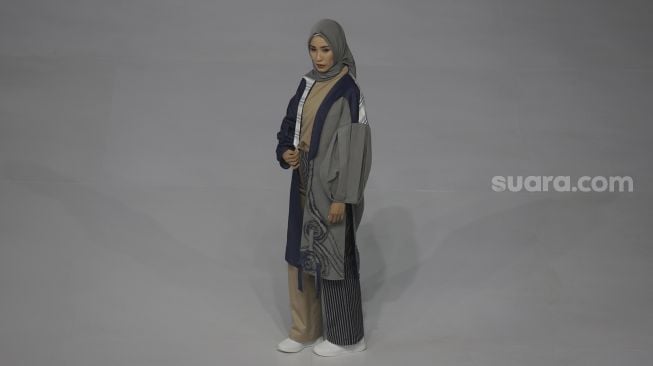 Model memperagakan busana muslim pada gelaran Jakarta Muslim Fashion Week (JMFW) di Stadion Aquatic, Gelora Bung Karno, Jakarta, Kamis (18/11/2021). [Suara.com/Angga Budhiyanto]