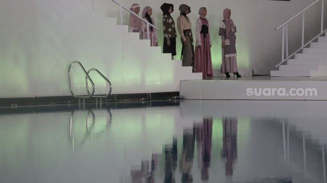 Model memperagakan busana muslim pada gelaran Jakarta Muslim Fashion Week (JMFW) di Stadion Aquatic, Gelora Bung Karno, Jakarta, Kamis (18/11/2021). [Suara.com/Angga Budhiyanto]