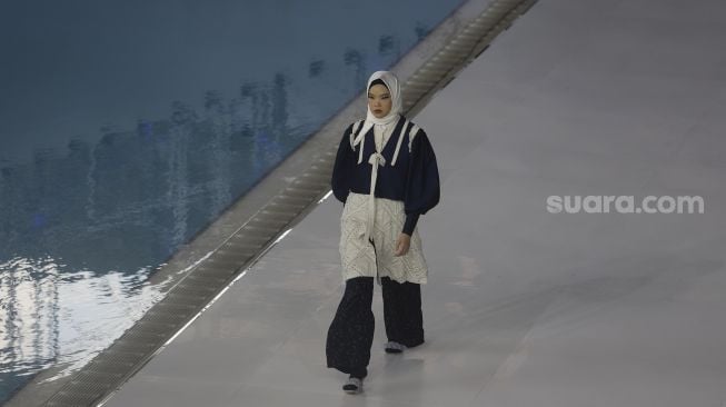 Model memperagakan busana muslim pada gelaran Jakarta Muslim Fashion Week (JMFW) di Stadion Aquatic, Gelora Bung Karno, Jakarta, Kamis (18/11/2021). [Suara.com/Angga Budhiyanto]