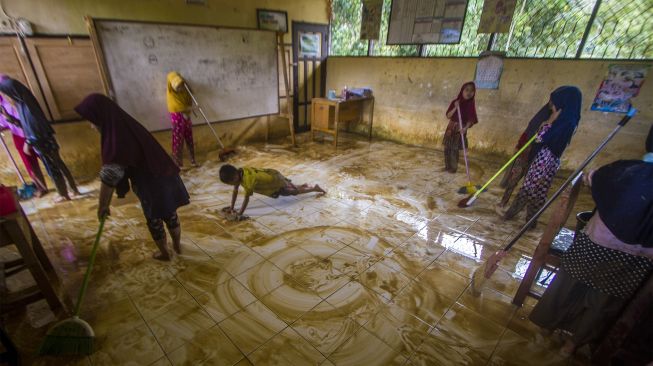 Sejumlah murid membersihkan ruang kelas SD Negeri Hantakan dari lumpur akibat meluapnya sungai Hantakan di Kecamatan Hantakan, Kabupaten Hulu Sungai Tengah, Kalimantan Selatan, Jumat (19/11/2021). [ANTARA FOTO/Bayu Pratama S]