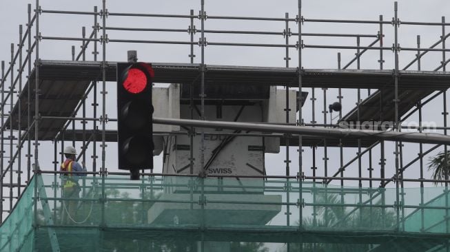 Sejumah kendaraan melintas di samping tugu jam yang dipasang perancah di Jalan MH. Thamrin, Jakarta, Jumat (19/11/2021). [Suara.com/Angga Budhiyanto]